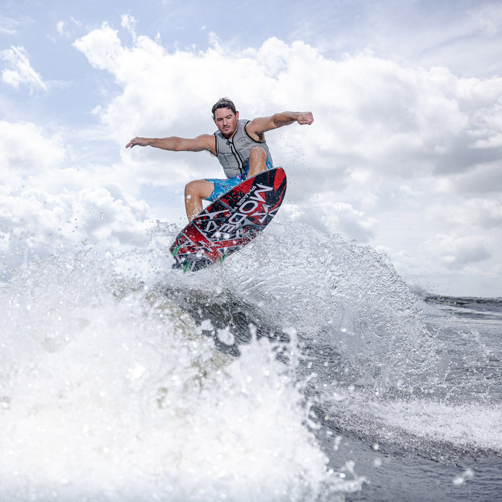 A person performs a jump on a wakeboard, showcasing the 2026 Phase Five Model X against a backdrop of water and clouds.