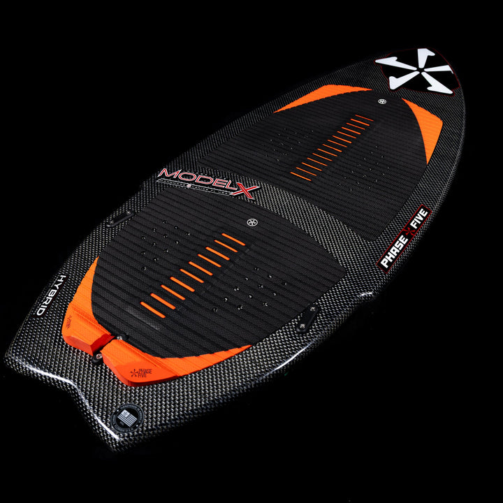 2026 Phase Five Model X wake surfboard featuring a sleek carbon fiber design with orange accents and textured grip.