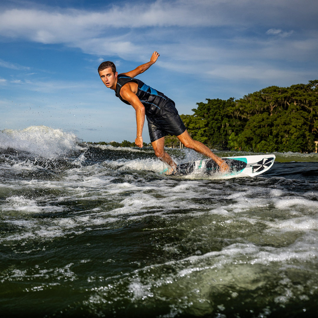 A surfer skillfully rides the waves on a 2026 Phase Five Phantom board, showcasing agility and style against a scenic backdrop.