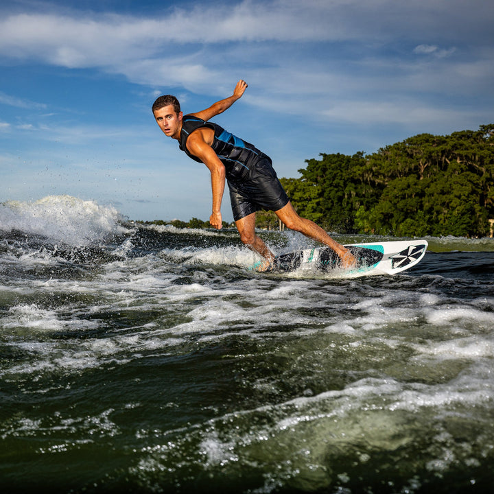 A surfer skillfully rides the waves on a 2026 Phase Five Phantom board, showcasing agility and style against a scenic backdrop.