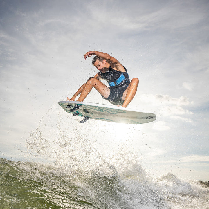 A surfer performs an aerial maneuver on a 2026 Phase Five Phantom board, showcasing skill and excitement on the water.