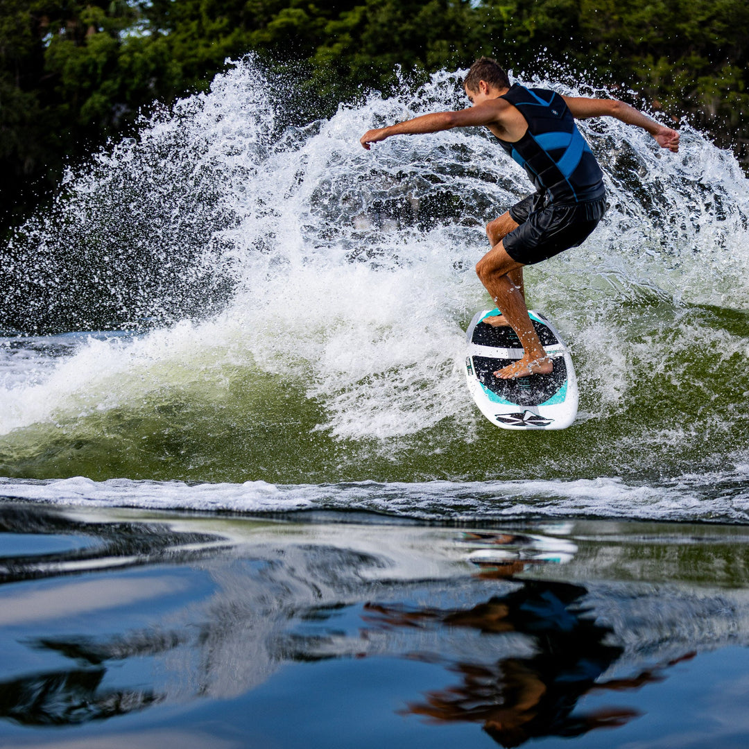A person riding the 2026 Phase Five Phantom wakesurf board, carving through a wave with water splashing around.