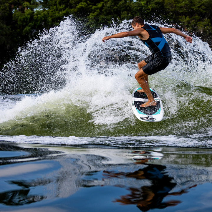 A person riding the 2026 Phase Five Phantom wakesurf board, carving through a wave with water splashing around.