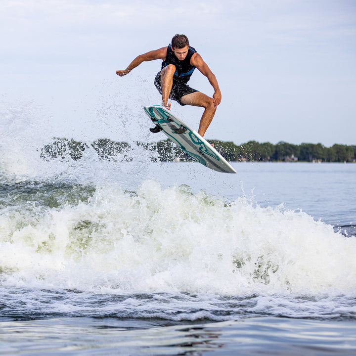 A person performs a jump on a 2026 Phase Five Phantom surfboard over a wave, showcasing dynamic water sports action.