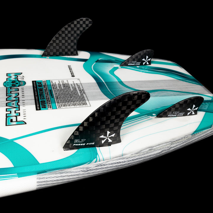2026 Phase Five Phantom surfboard featuring a sleek design with three carbon fins and vibrant teal accents.
