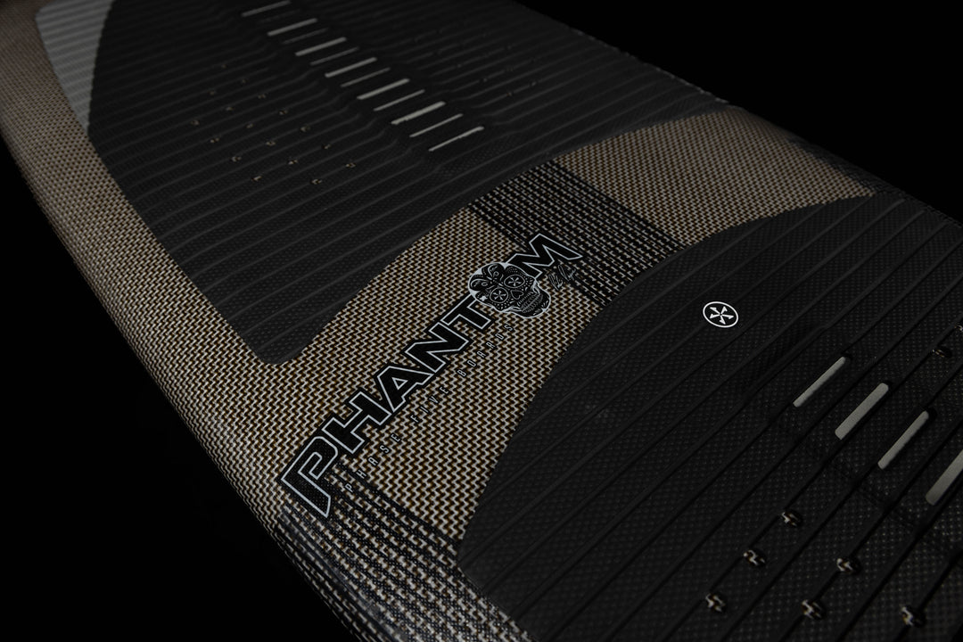 Close-up of the 2025 Phase 5 Phantom Stealth surfboard featuring textured grip pads, black and gold design, and brand logo.