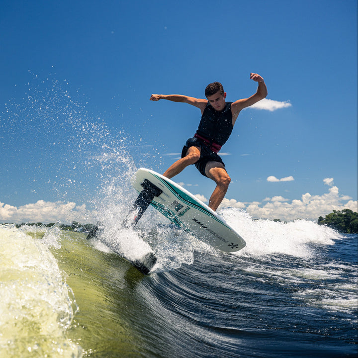 A rider performs a jump on the 2026 Phase Five Phantom Foil, showcasing its design on a sunny day over water.