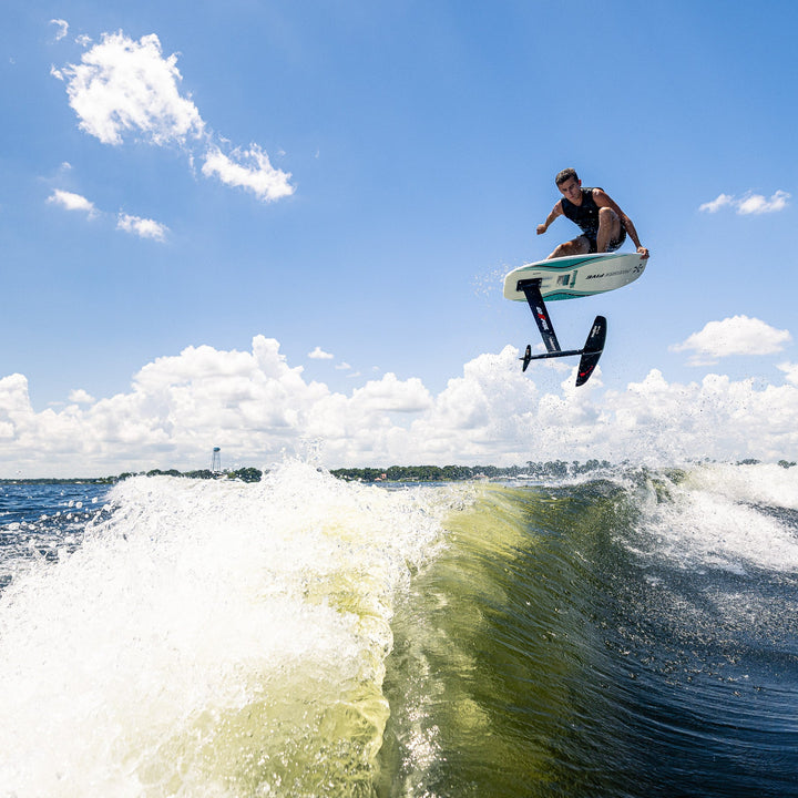 A rider performs a jump on the 2026 Phase Five Phantom Foil above a wave, showcasing the excitement of water sports.