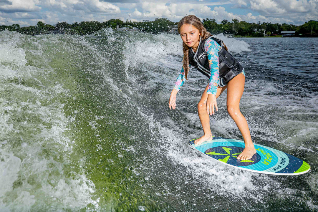 Young girl riding a wave on the 2025 Phase 5 Snapper Skim Board on a river or lake.