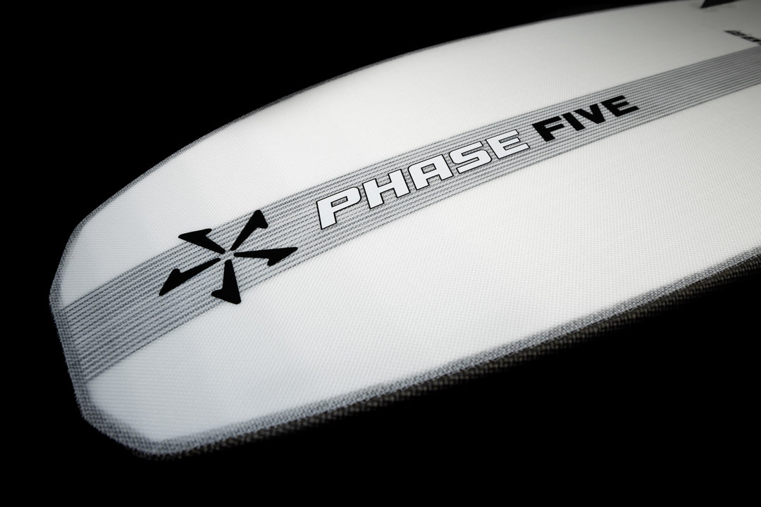 Close-up of the 2025 Phase 5 Phantom Stealth Surf Board with a sleek white design, black logo, and gray stripe on a black background.