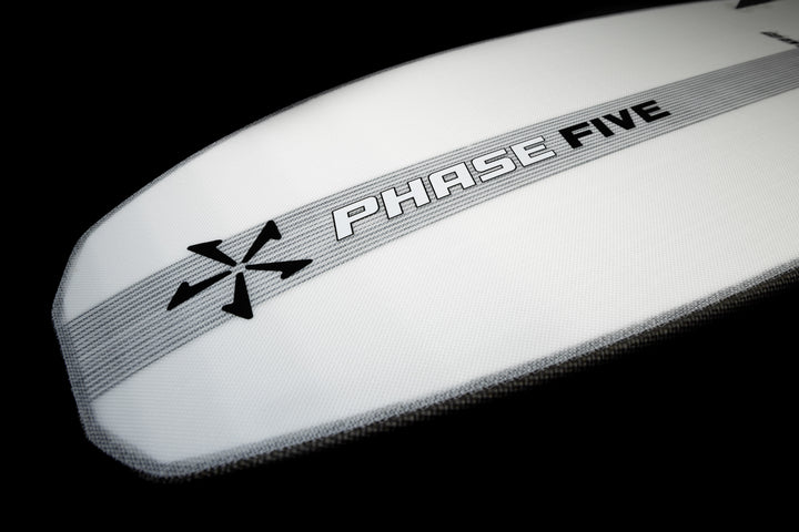 Close-up of the 2025 Phase 5 Phantom Stealth Surf Board with a sleek white design, black logo, and gray stripe on a black background.
