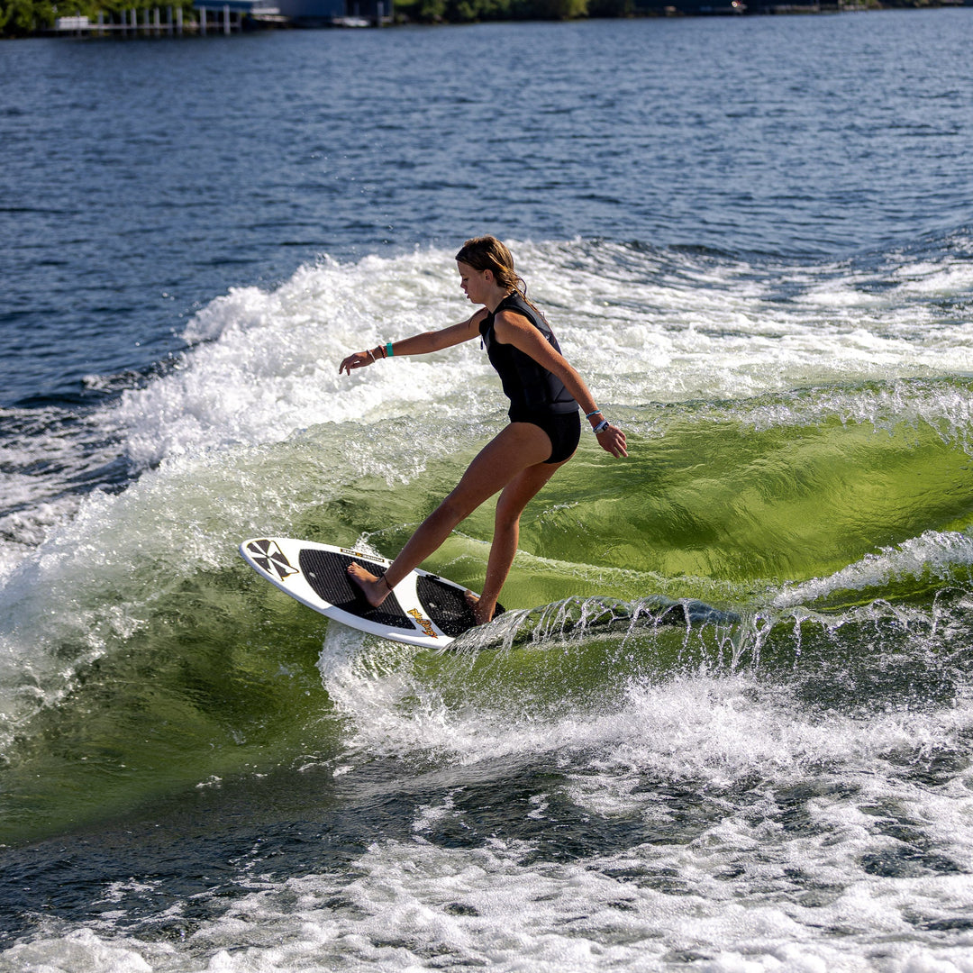 A person surfing on a 2026 Phase Five Surfari board, riding a green wave on a sunny day.