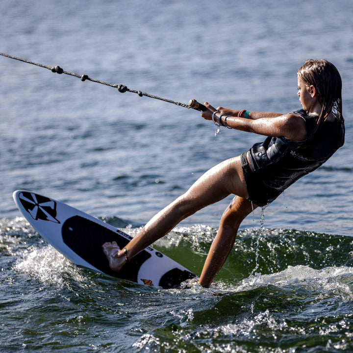 A young person wakesurfing on a 2026 Phase Five Surfari board, gliding over the water with a rope in hand.