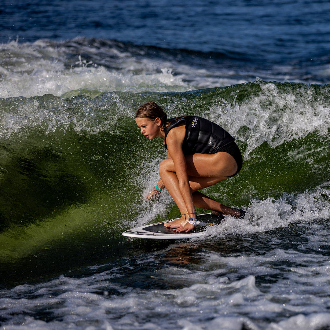 A person riding a wave on a 2026 Phase Five Surfari surfboard, showcasing skill and balance in a vibrant water setting.