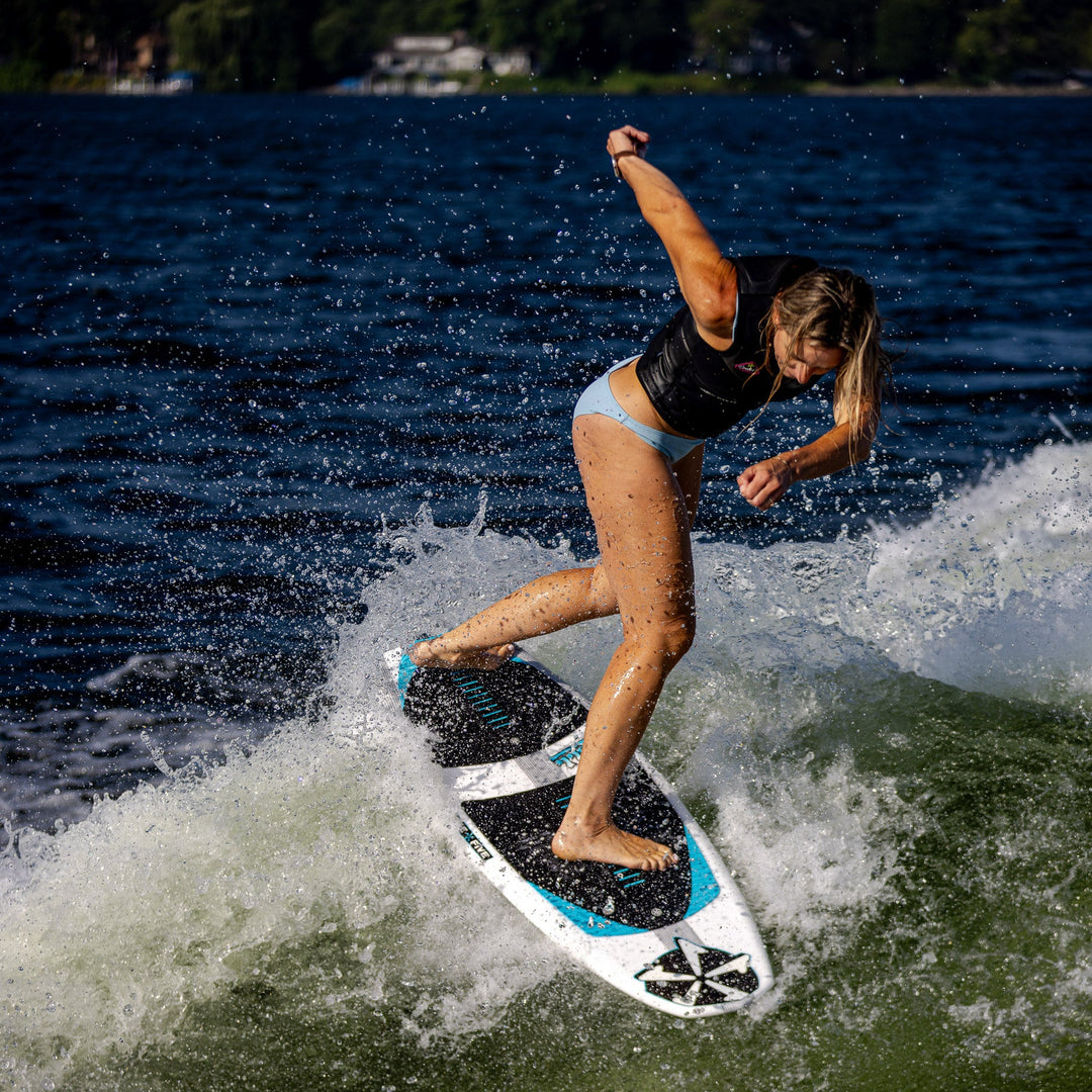 A woman surfing on the 2026 Phase Five Swell board, carving through a wave on a sunny day.