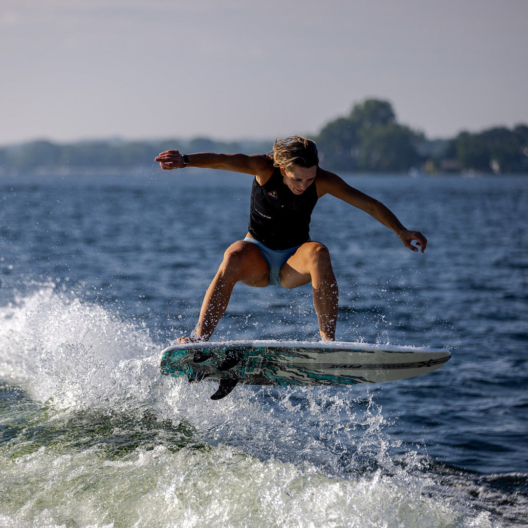 A person performs a jump on a 2026 Phase Five Swell surfboard, creating a splash on the water.