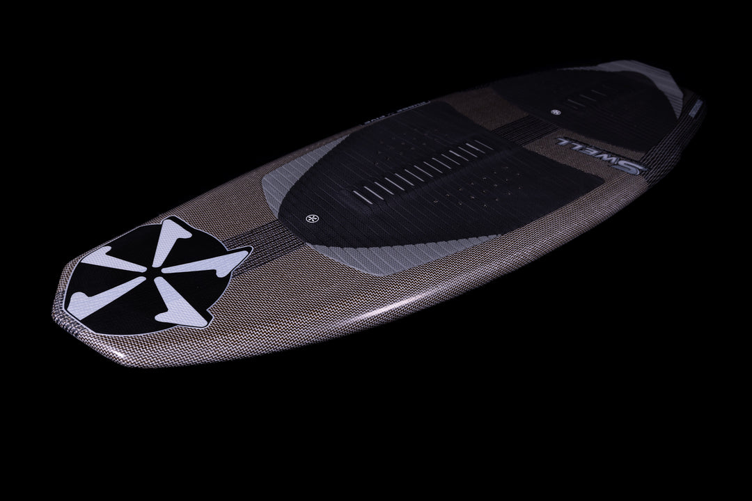 2025 Phase 5 Swell Stealth surfboard with a sleek, textured design, black traction pad, and prominent logo on a black background.