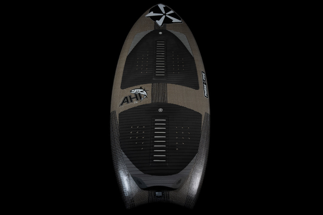 2025 Phase 5 Ahi Stealth surfboard with black traction pads and sleek design, shown from a top-down view against a black background.