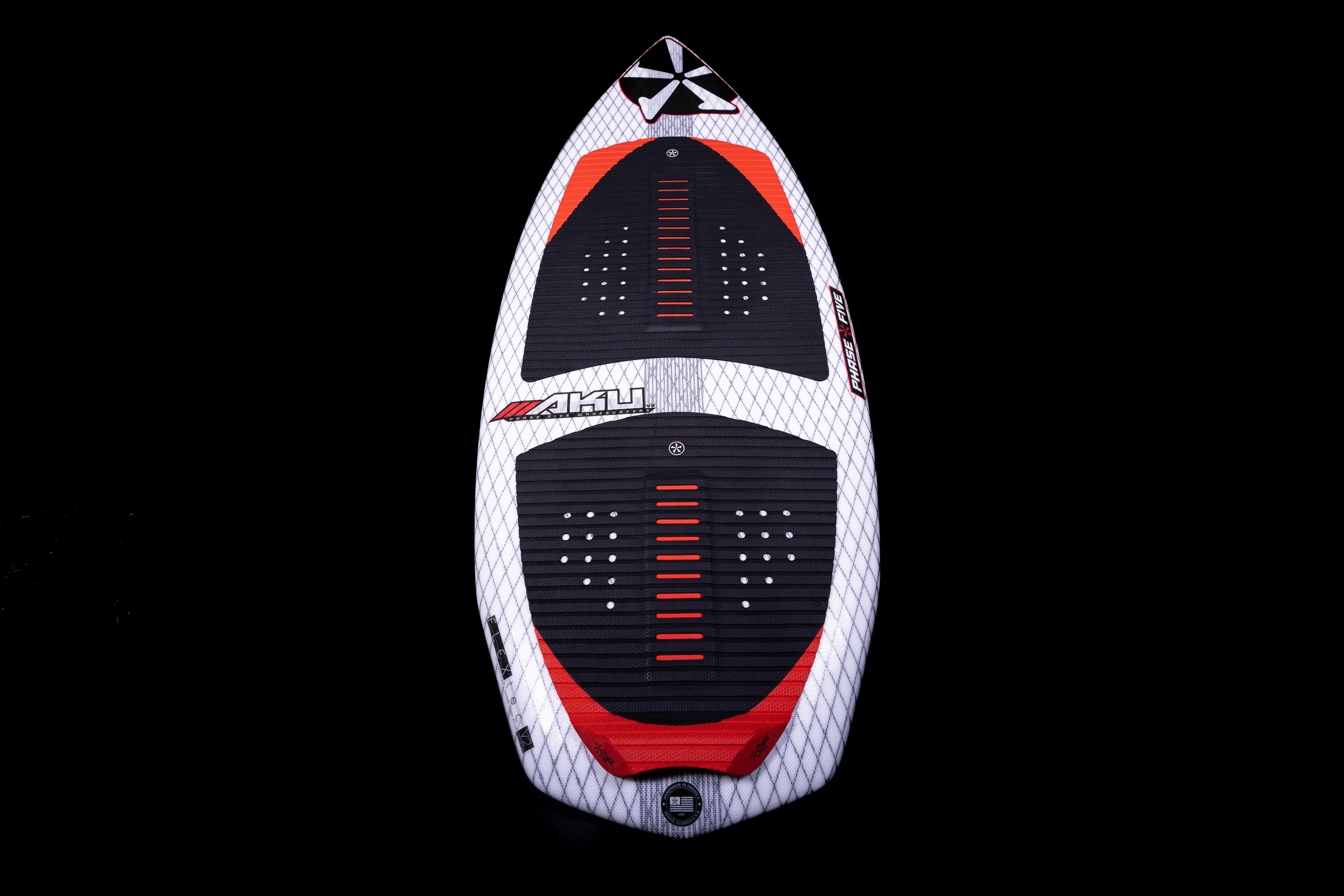 Top view of the 2025 Phase 5 Aku Surf Board with black, red, and white design, featuring traction pads and fin attachments.