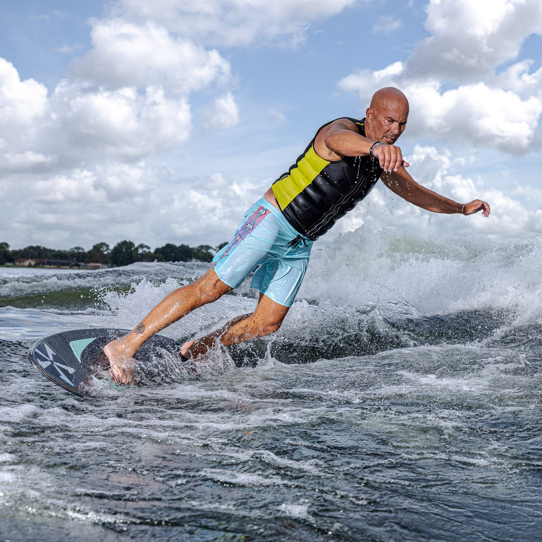 A man rides the 2026 Phase Five Trident V3 surfboard on a wave, showcasing dynamic movement and water spray.