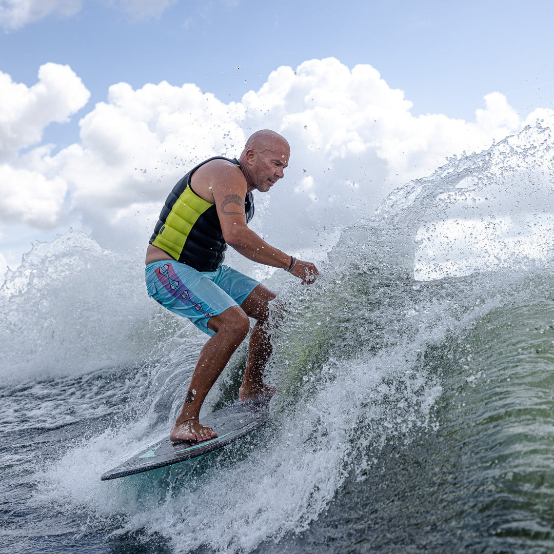 Man surfing on a wave with the 2026 Phase Five Trident V3 board, showcasing dynamic movement and water spray.