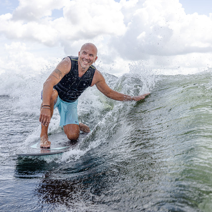 A person riding the 2026 Phase Five Trident V3 surfboard, carving through a wave with a smile on a sunny day.