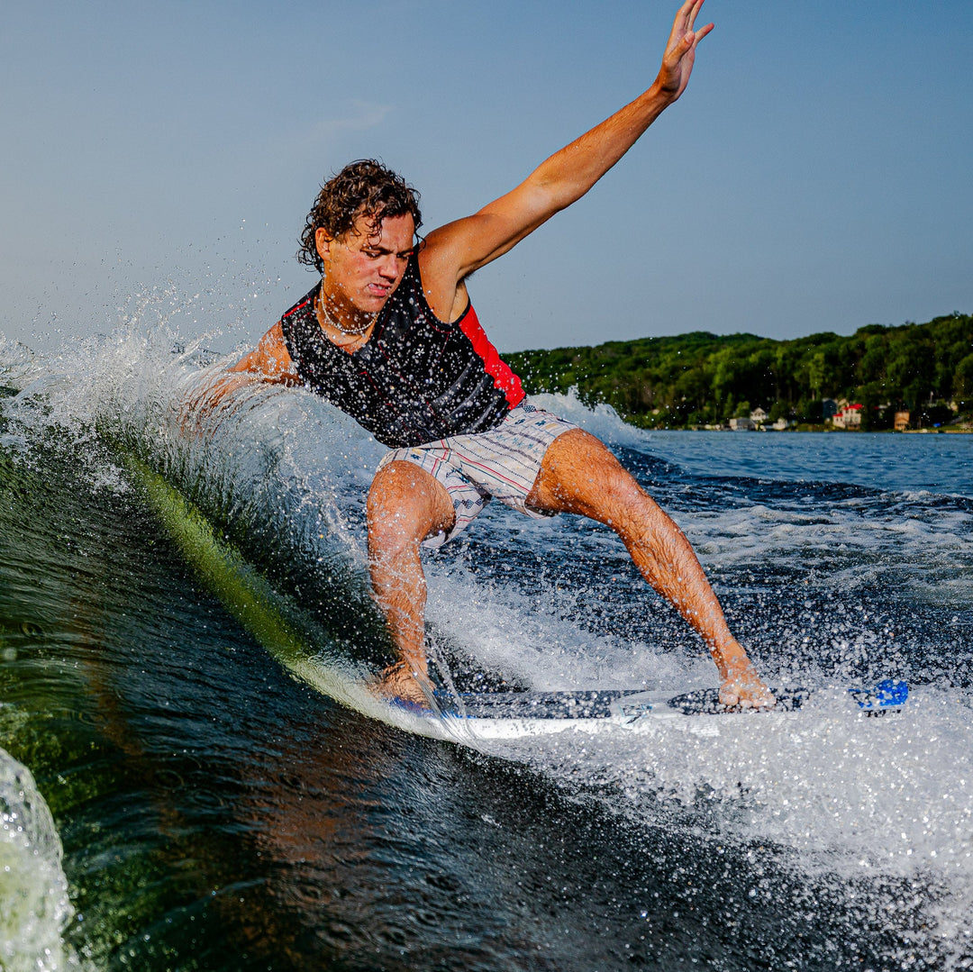 A surfer performs a trick on the 2026 Phase Five Viper board, creating splashes on a sunny lake.