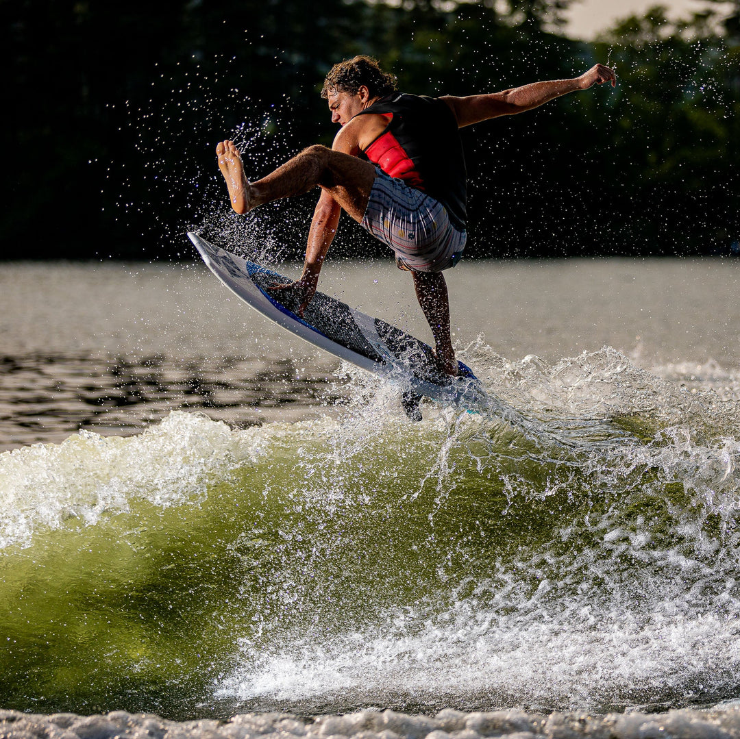 A person performs a jump on a 2026 Phase Five Viper surfboard, creating a splash on a wave.