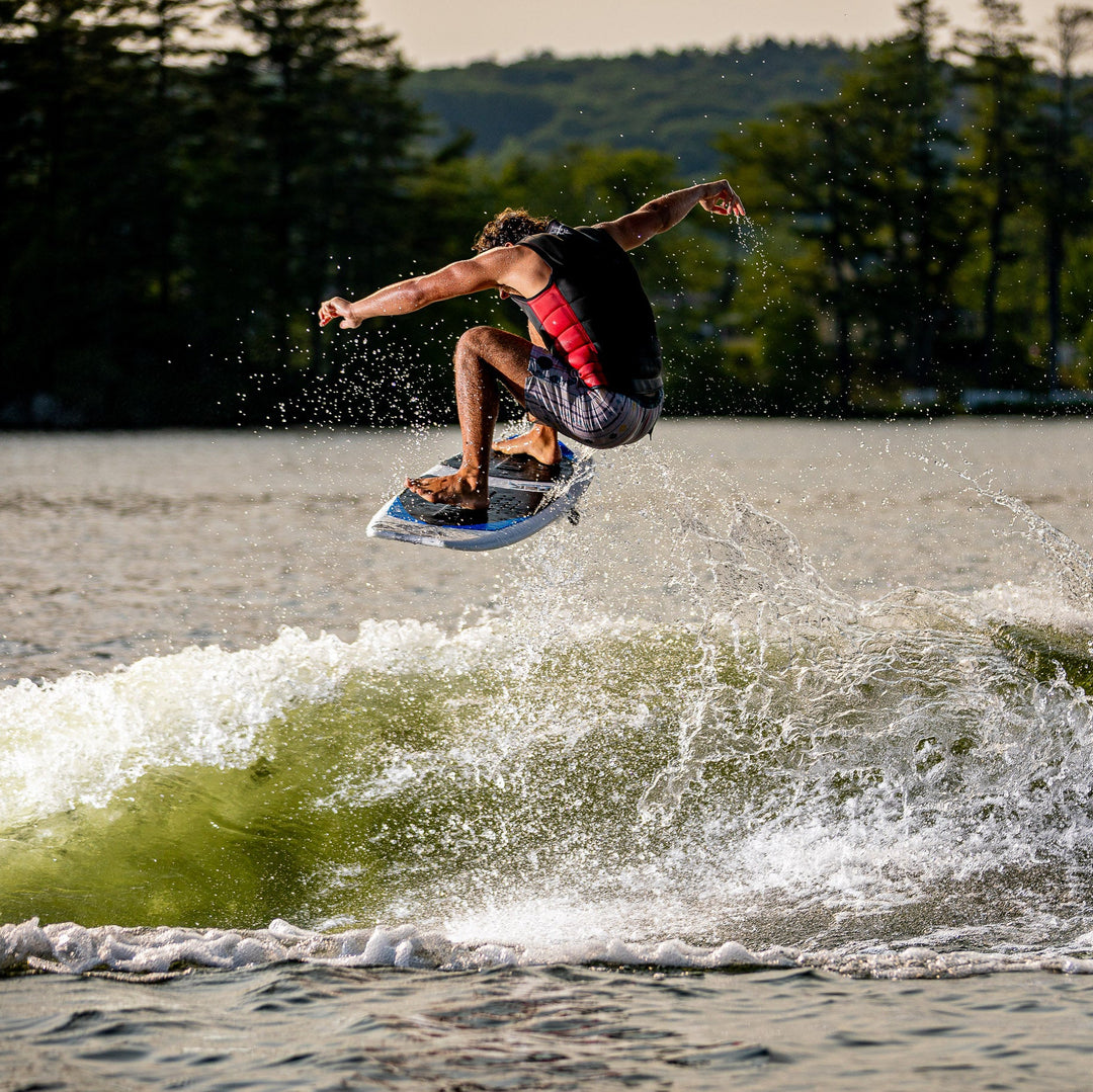 A person performing a jump on a 2026 Phase Five Viper surfboard over a green wave, showcasing dynamic water sports action.