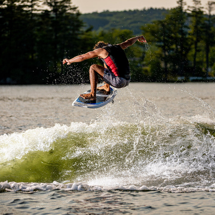 A person performing a jump on a 2026 Phase Five Viper surfboard over a green wave, showcasing dynamic water sports action.