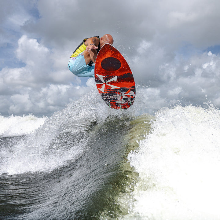 A person performs a jump on a 2026 Phase Five XB surfboard over a wave, showcasing dynamic water sports action.