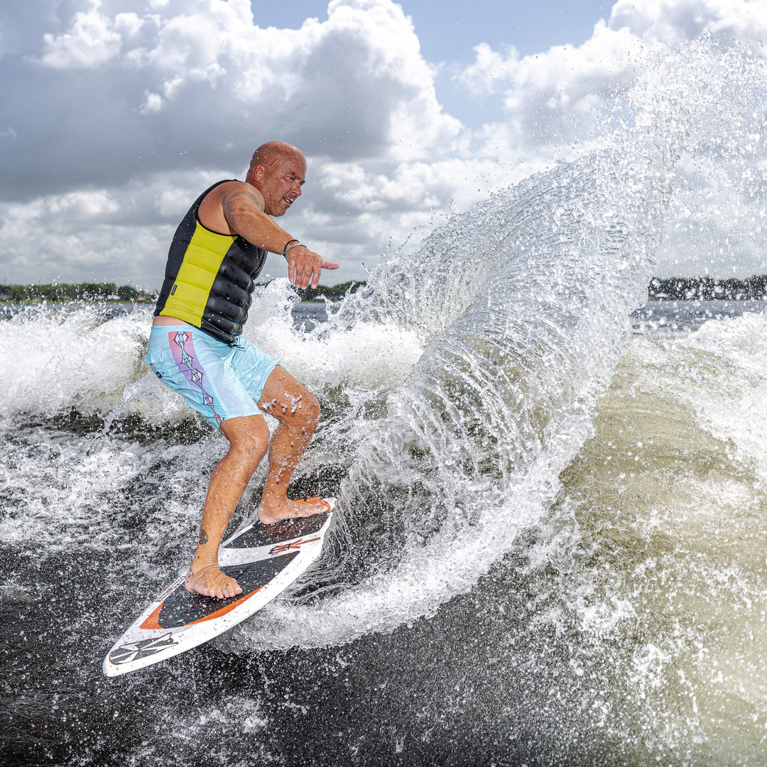 A surfer riding the 2026 Phase Five XB wakesurf board, carving through a wave with a dynamic spray of water.