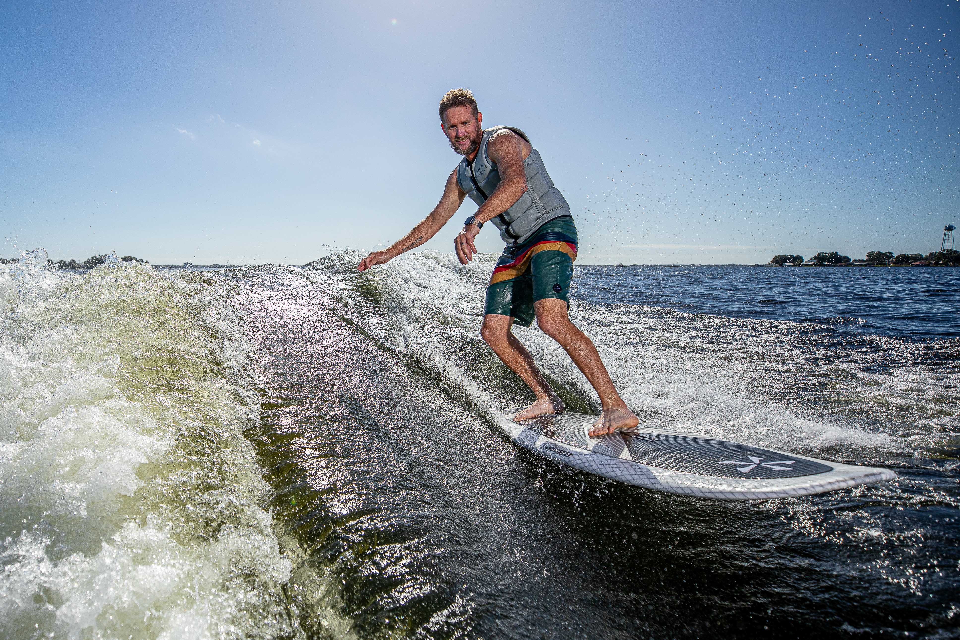Man surfing on the 2025 Phase 5 Zilla Surf Board on open water during daytime.