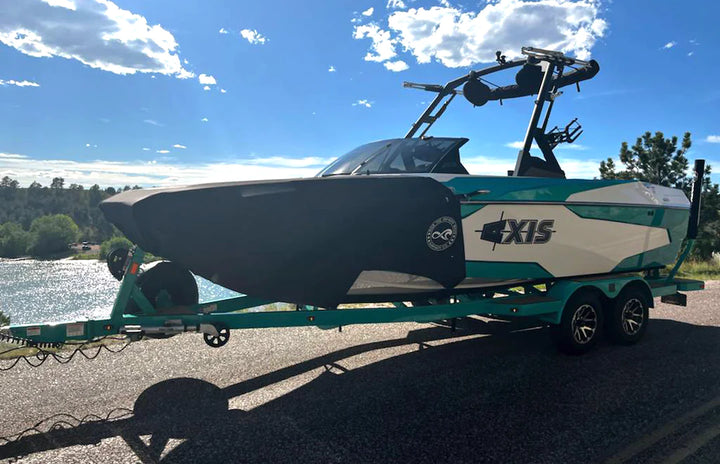 Axis Boat Shield by SURFINITY installed on a boat trailer, protecting the boat from debris and water spray during transport.
