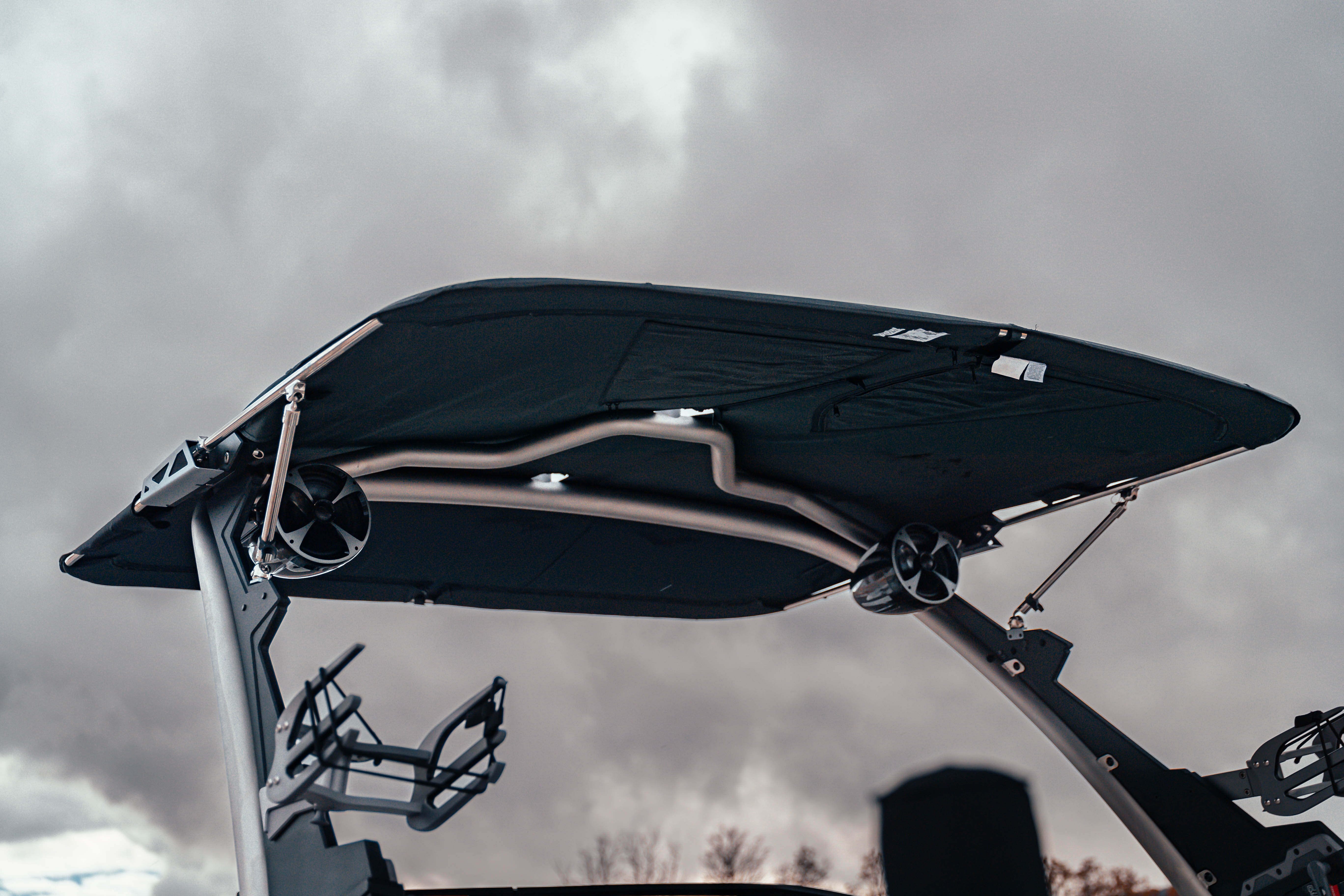 GV Complete Slider Bimini with Extension installed on a boat, featuring a black fabric canopy and metal frame against cloudy sky.