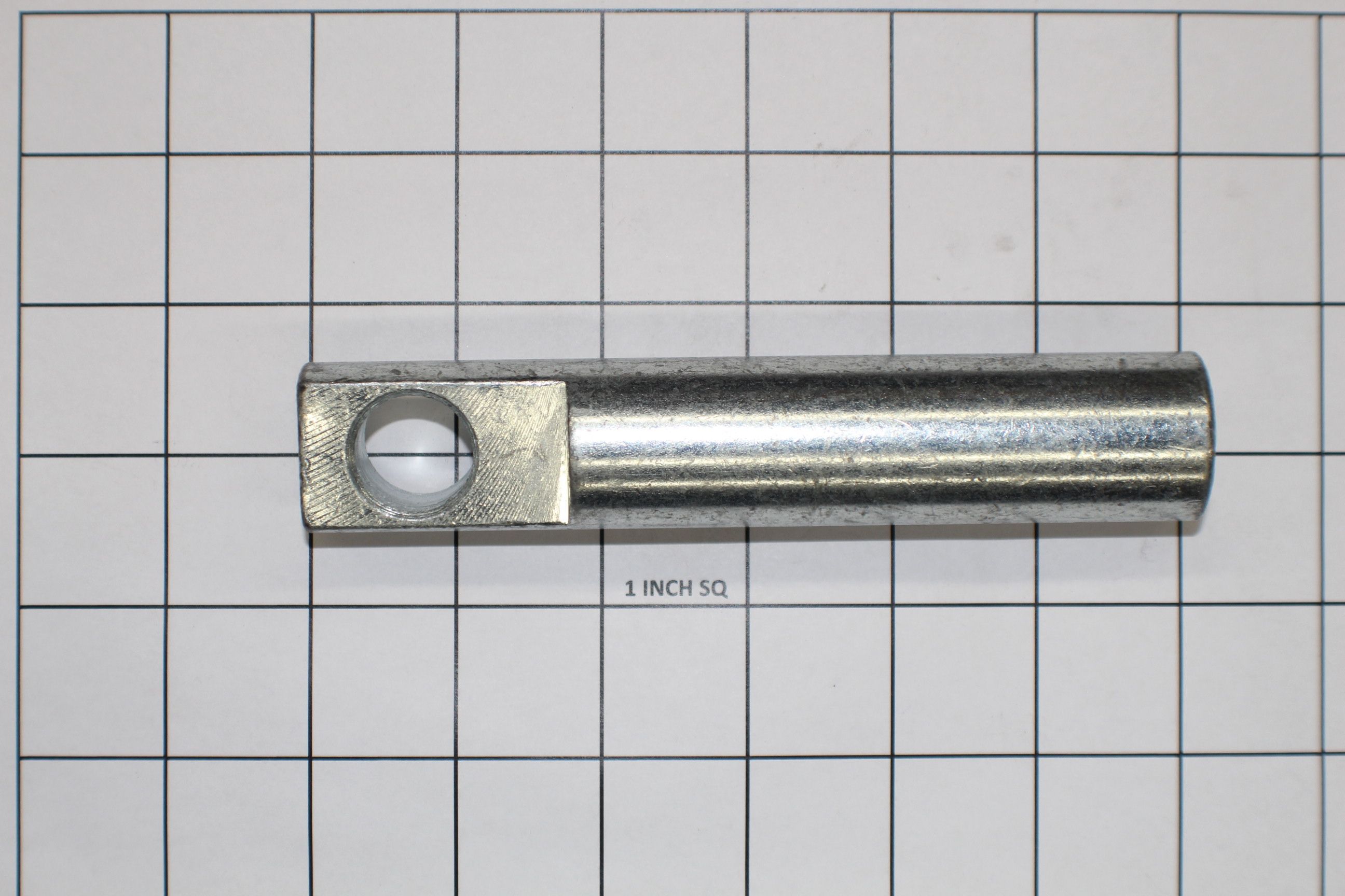 Metal bar trunnion with a circular hole, measuring approximately 4 inches in length, on a grid background.