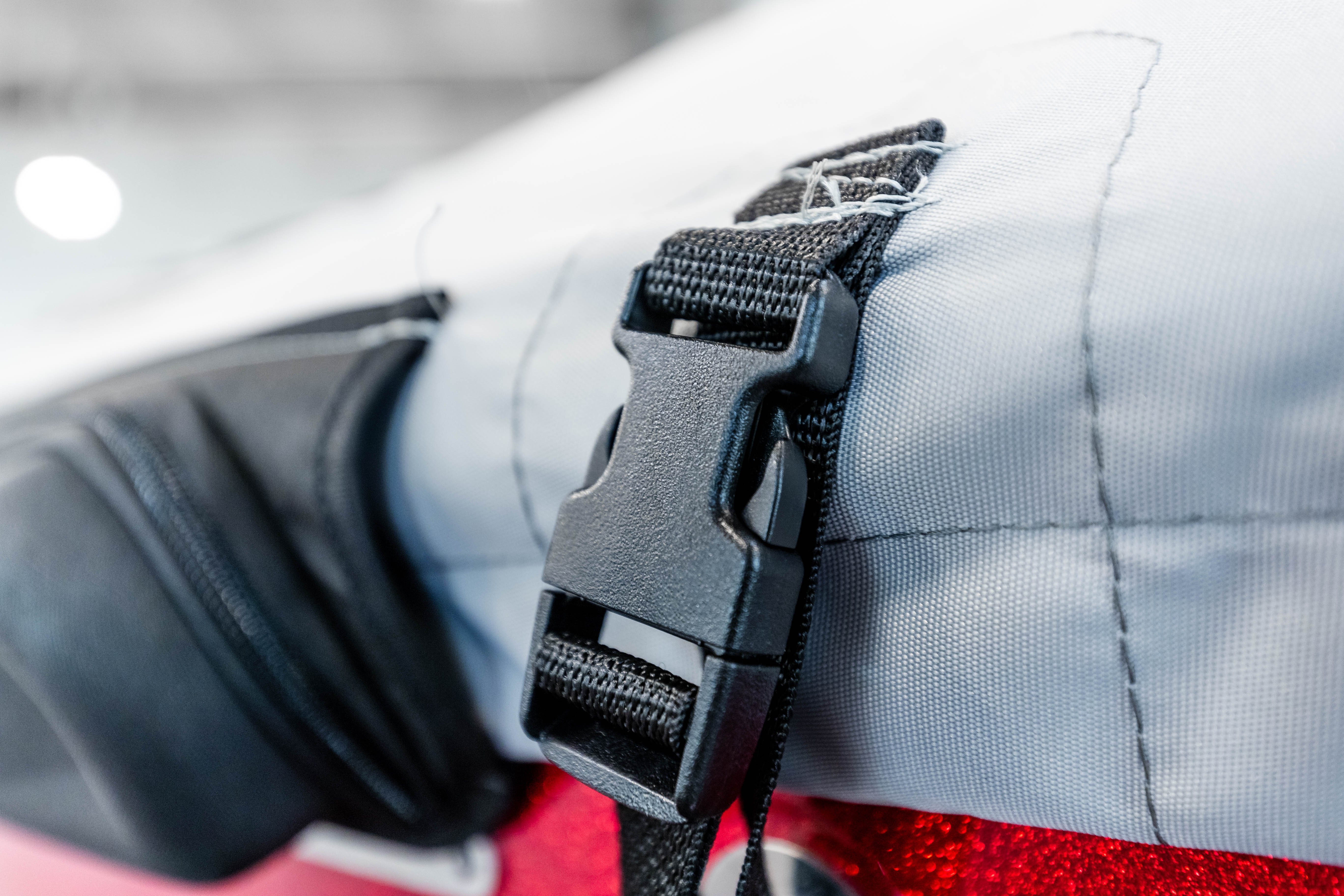 Close-up of a black buckle on an A24 Cover for Axis AW20 Tower with Swim Platform Cover & TAPS 2.5, attached to gray fabric material.