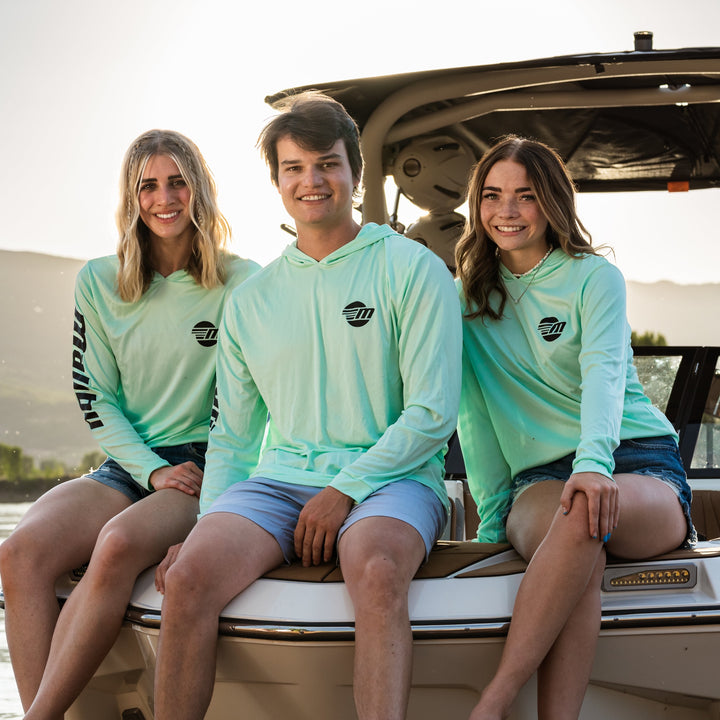 Three people sitting on a boat wearing Shaded Shredder Sun Hoodies in Malibu, enjoying a sunny outdoor day.