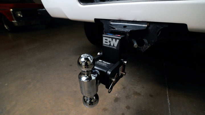 Black B&amp;W Tow &amp; Stow adjustable ball mount with chrome hitch ball attached to a vehicle&