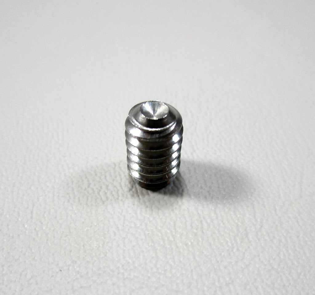 Close-up of a small, shiny metal tower handle set screw with threaded body on a white textured surface.