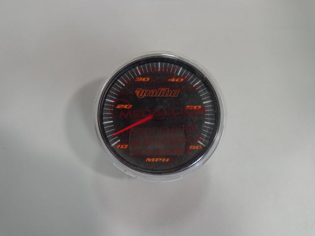 Speedometer gauge with a black face, red needle, and white markings, featuring a W/LCD display for speed measurement in MPH.