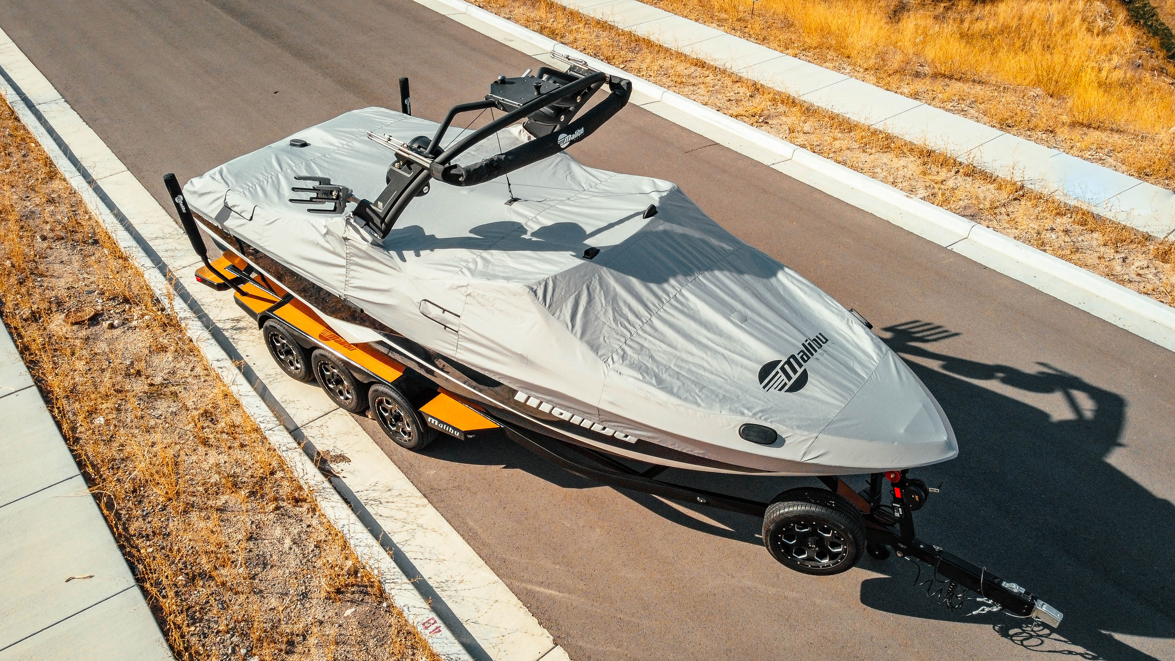 2018 25 LSV boat covered with a gray protective cover, featuring a G3.5 tower and swim platform, parked on a road.